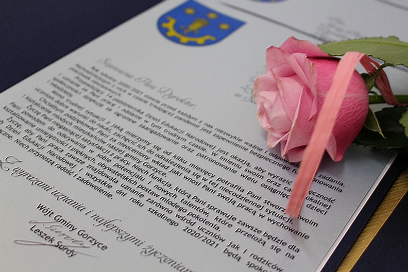   Zdjęcie treści podziękowania, jakie otrzymali dyrektorzy i nauczyciele podpisane przez Wójta Gminy Gorzyce - Leszka Surdego. Na kartce podziękowań leży róża w kolorze różowym, przewiązana wstążeczka w tym samym kolorze.