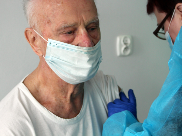 Na zdj. Pielęgniarka podaje pacjentowi szczepionkę przeciw COVID-19