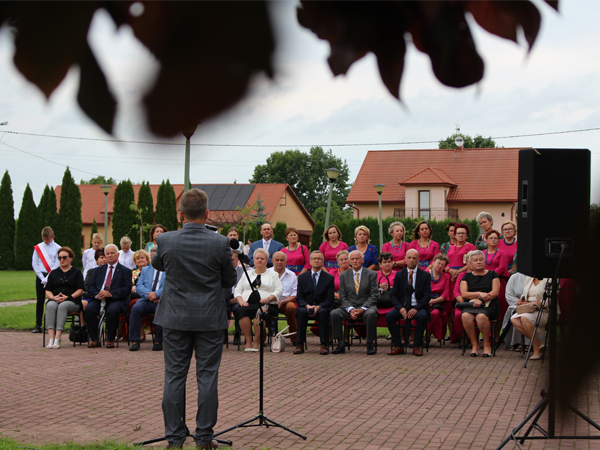 W tle zdjęcia - zaproszeni goście i mieszkańcy Wrzaw, słuchają uroczystego odczytu poświęconego historii parafii Wrzawy. 